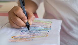 Pupil writing in exercise book and circling words in different colours