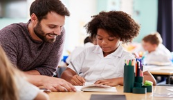 Teacher helping student with writing in their class